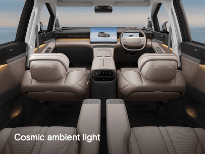 interior mobil dengan nuansa premium yang didominasi warna terang dan pencahayaan ambient di sepanjang dashboard dan pintu. Kabin terlihat luas, bersih, dan modern, dengan kursi besar yang memberikan kesan nyaman.