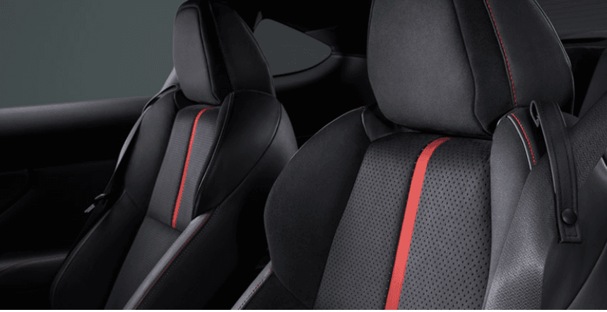 kursi sport dengan material ultra-suede hitam yang dilengkapi aksen garis merah vertikal, dirancang ergonomis untuk menahan posisi tubuh tetap stabil saat menikung.