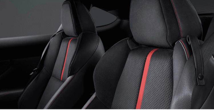 kursi sport dengan material ultra-suede hitam yang dilengkapi aksen garis merah vertikal, dirancang ergonomis untuk menahan posisi tubuh tetap stabil saat menikung.